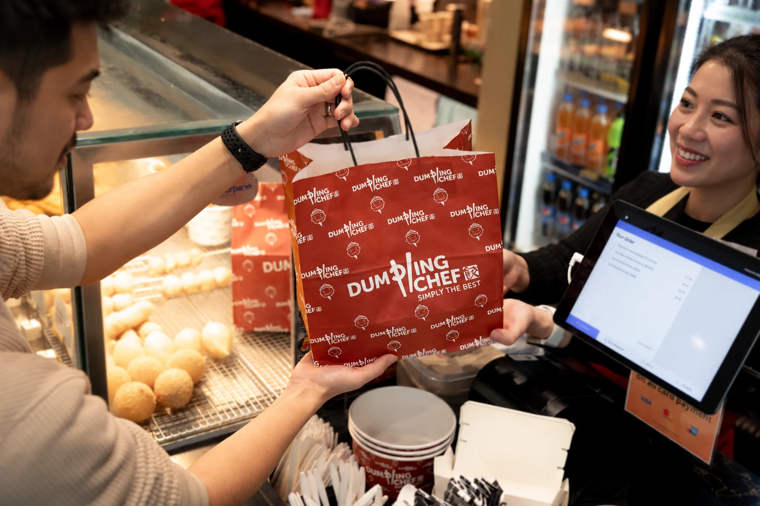 A takeaway bag handover at the Dumpling Chef counter, with AI-replaced fictional faces